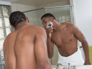 black man in shower shaving