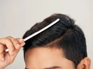 man combing his hair with a small comb