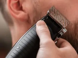 man using beard trimmer on facial hair