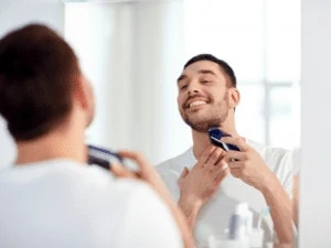 man wearing white shirt shaving his beard